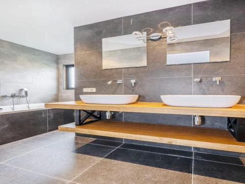 a bathroom with two sinks and a mirror at Modern lodge stay with pond view in Schaluinen