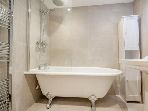 a bathroom with a white tub and a shower at 2 Bed in Porthmadog 93835 in Penrhyndeudreath