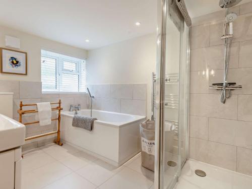 a bathroom with a tub and a shower and a sink at 3 Bed in Godshill Wood 94495 in Godshill