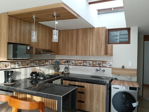 eine Küche mit Holzschränken und einer schwarzen Arbeitsplatte in der Unterkunft Minidepa con vista al Misti, near Plaza de Armas in Arequipa