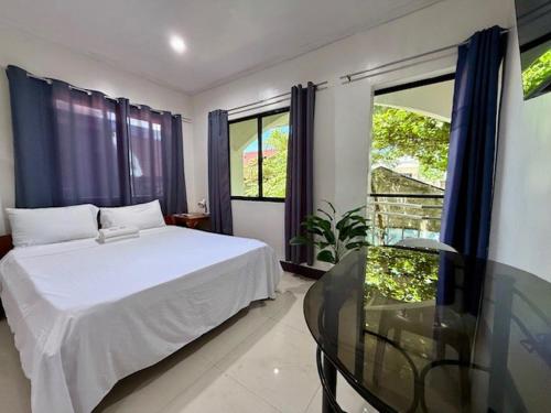 a bedroom with a white bed and a glass table at DRB Siargao Apartments in General Luna