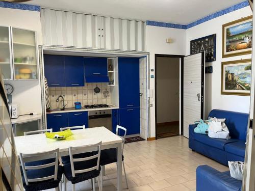 a kitchen with blue cabinets and a table and a blue couch at Appartamento a 20 metri dal mare San Salvo Marina in Marina di Montenero