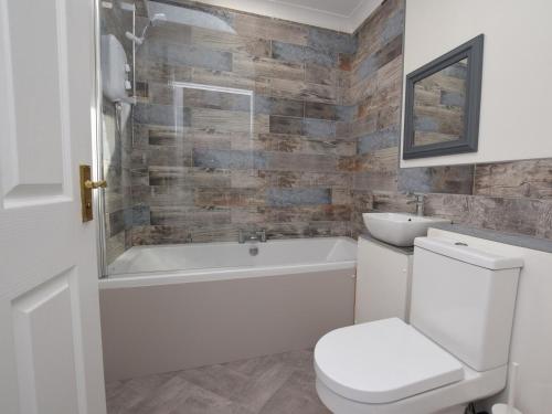 a bathroom with a toilet and a tub and a sink at 1 Bed in Biggar 82923 in Biggar
