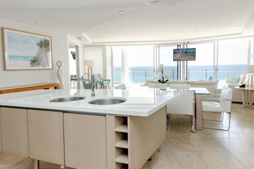a kitchen with two sinks and a living room at 5-Star Beachfront Retreat with Theatre & Pool in Mooloolaba