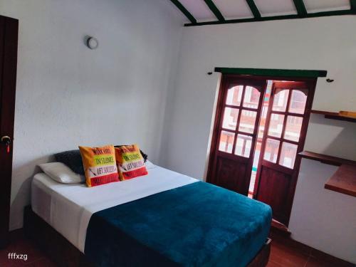 a bedroom with a bed with two pillows and a window at Roomiie Hostel in Villa de Leyva