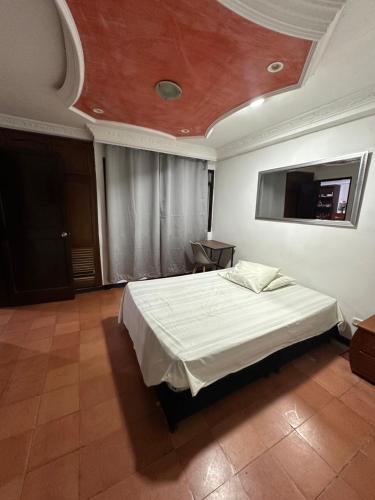 a bedroom with a large bed with a white bedspread at La Casona Hostal in Pereira