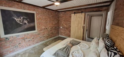 a room with a bed and a brick wall at Singwe Private Safari Lodge Kruger in Marloth Park