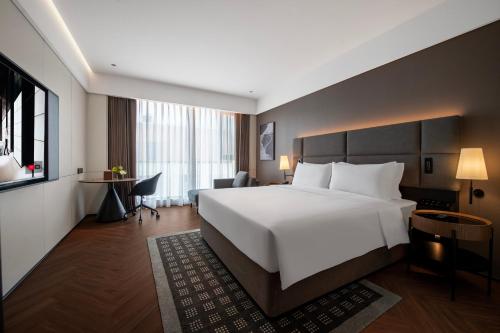a hotel room with a large white bed and a desk at 上海虹桥中心城际酒店 in Shanghai