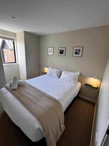 a bedroom with a large white bed with two lamps at Queenstown Retreat in Queenstown