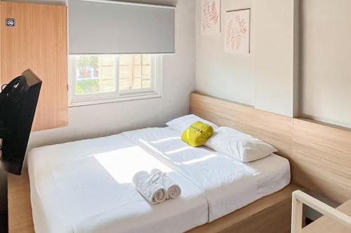 a bedroom with a bed with two towels on it at Urbanview Hotel The Tang Balikpapan by RedDoorz in Balikpapan