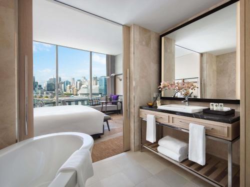a bathroom with a tub and a bed and a sink at Sofitel Sydney Darling Harbour in Sydney