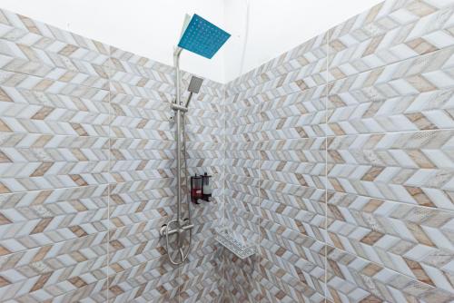 a shower in a bathroom with a brick wall at Urbanview Hotel The Tang Balikpapan by RedDoorz in Balikpapan