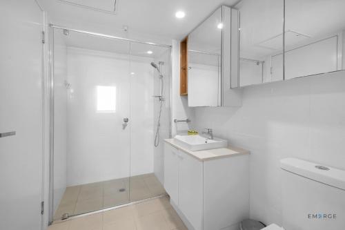 a white bathroom with a shower and a sink at Mowbray East Apartments in Brisbane