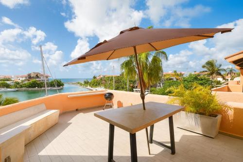 a wooden table with an umbrella on a balcony at Ocean & Marina views,Affordable,Spoil yourself! in Puerto Aventuras