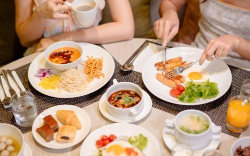 een groep mensen aan een tafel met borden eten bij Dusit Princess Chiang Mai in Chiang Mai