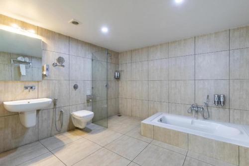 a bathroom with a tub and a toilet and a sink at Palette - Silver Leaf in Vapi