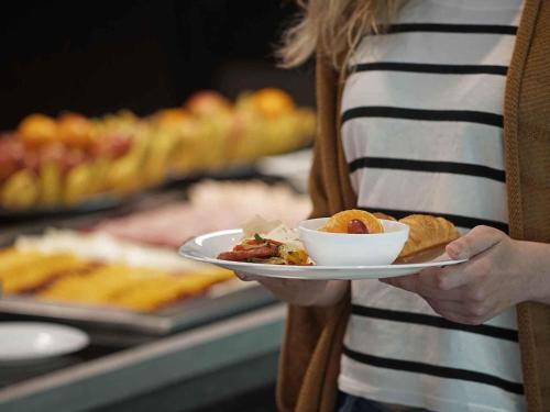 オザスコにあるibis Osascoの女が一皿の食べ物を持っている