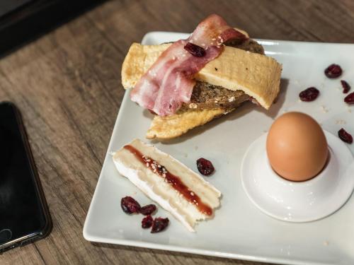 Un plato blanco con un huevo y algo de comida. en Ibis Styles Toulouse Blagnac Aéroport, en Blagnac