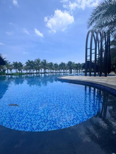 a large swimming pool with palm trees in the background at MYSTERY HOME - NOVAWORLD PHAN THIET 3BR 120m2 in Bình Tú