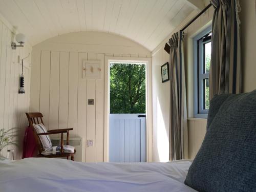 a bedroom with a bed and a large window at Blackstairs Shepherds Huts in Killedmond