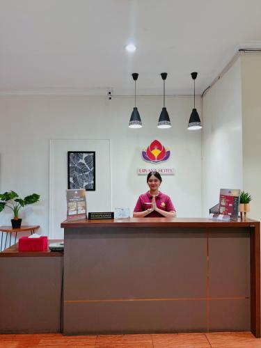 a woman standing behind a counter in a room at URVANA Hotel By Majestra Hospitality in Kamparganya
