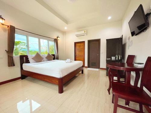 a bedroom with a bed and a table and a desk at janwareeresort in Sangkhla Buri