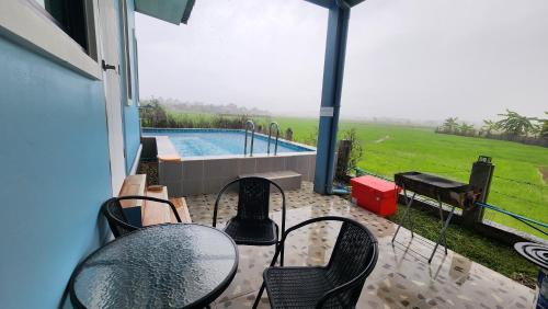 Un patio con mesas y sillas y una piscina. en บ้านกลางนาพูลวิลล่า, en Nan