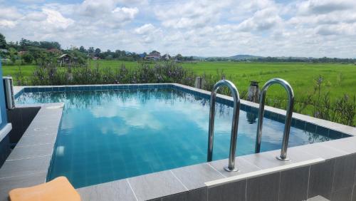 a swimming pool with a view of a field at บ้านกลางนาพูลวิลล่า น่าน in Nan