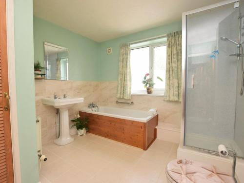 a bathroom with a bath tub and a sink at 3 Bed in Gower 72846 in Port-Eynon