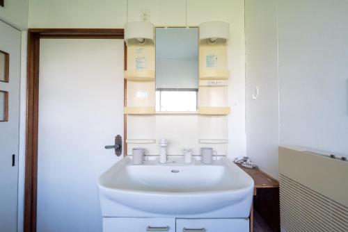 a bathroom with a white sink and a mirror at Kamifurano House in Kami-furano