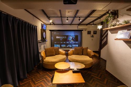 a living room with two chairs and a flat screen tv at Cinema Resorts 1 in Motobu