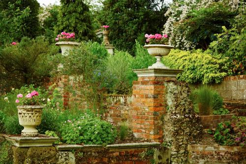 a garden with two vases with flowers on a brick wall at Bromley Court Hotel London in Bromley