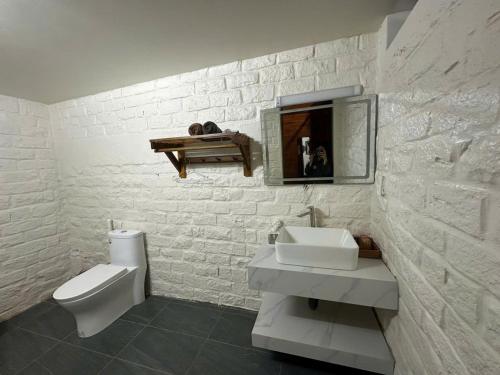 a white bathroom with a sink and a toilet at Ecohouse Hòn Sơn in Lai Sơn