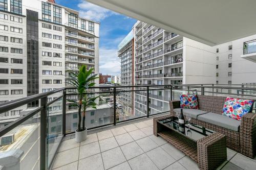 a balcony with two chairs and a plant on it at Sky Tower View with Rooftop Pool! in Auckland