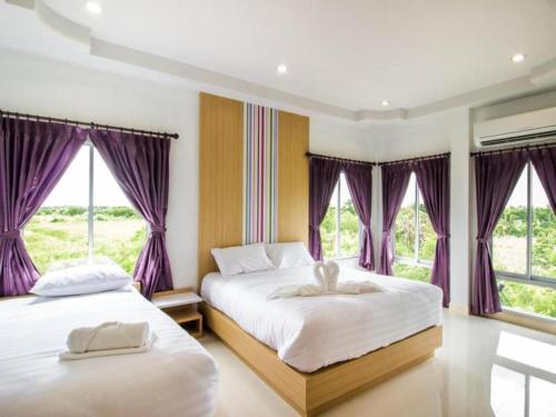 two beds in a bedroom with purple curtains at Eitanic Resort in Ban Don Tako