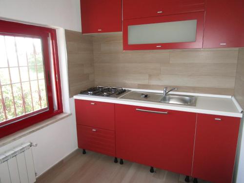 マッサ・ルブレンセにあるVilla Staraceのキッチン(赤いキャビネット、シンク、窓付)