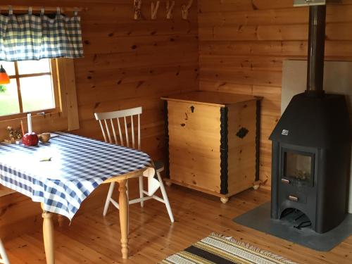 a room with a stove and a table and a table and chair at Stuga vid Hedenäsets stencafé in Hedenäset