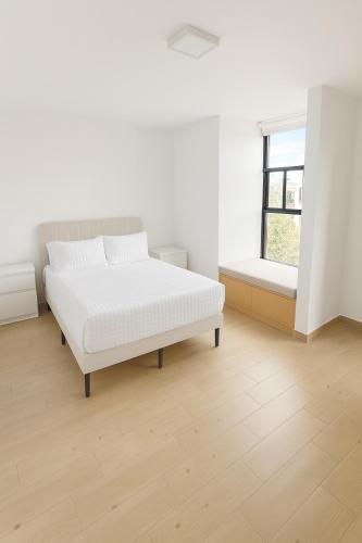 a white bedroom with a bed and a window at Depamor in Morelia