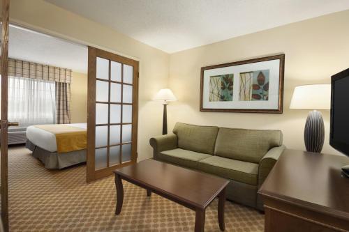 a hotel room with a couch and a bed at Country Inn & Suites by Radisson, Owatonna, MN in Owatonna