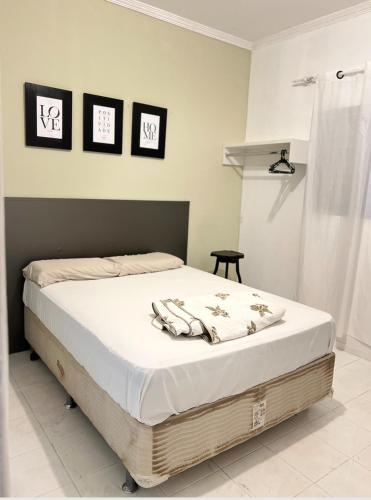 ein Bett in einem Schlafzimmer mit drei Bildern an der Wand in der Unterkunft Casa De Ferias No Centro De Caldas Novas in Caldas Novas