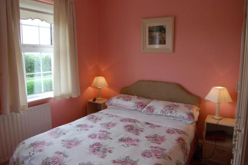 a bedroom with a bed with pink walls and two windows at Ballingowan House in Newcastle West