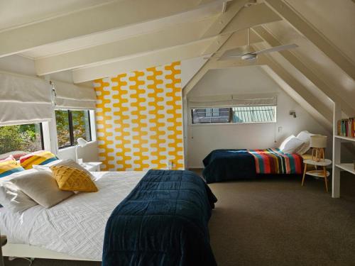 1 dormitorio con 2 camas y pared amarilla y blanca en Forest Waters Bungalow, en Haruru