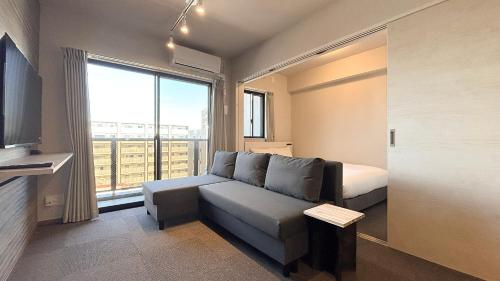 福岡市にあるLiving like hotel Hakata Premiumのソファとベッドと窓のある部屋
