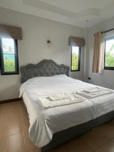 a bedroom with a bed with white sheets and windows at บ้านกลางนาพูลวิลล่า น่าน in Nan