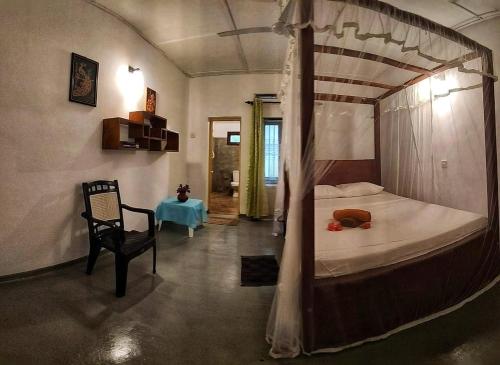une chambre avec un lit à baldaquin et une chaise dans l'établissement Beach House Madiha, à Matara