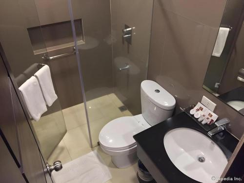 a bathroom with a toilet and a glass shower at GT Hotel Bacolod in Bacolod