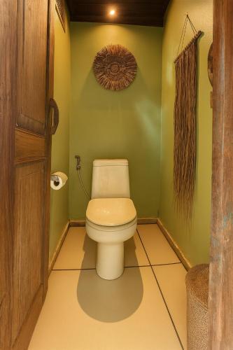 a bathroom with a toilet in a green wall at Barefoot in the Heart in Krambitan