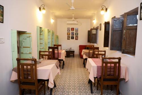a restaurant with tables and chairs with pink tablecloths at U-trn home stay in Bikaner
