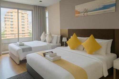a hotel room with two beds with yellow pillows at The Wooden Nest Warm Stay at Sukhumvit 8 in Bangkok