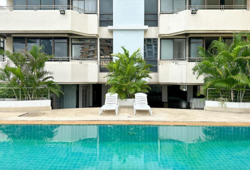 two chairs by a swimming pool in front of a building at The Wooden Nest Warm Stay at Sukhumvit 8 in Bangkok